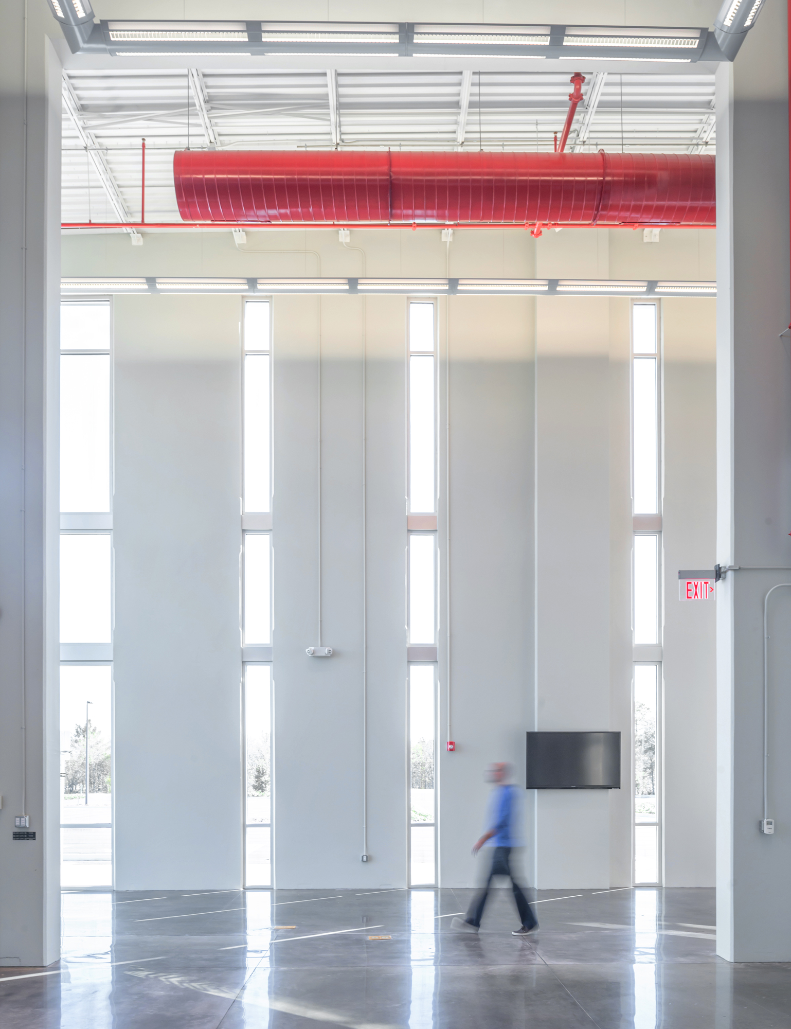 industrial lobby with floor-to-ceiling windows and exposed red ductwork and steel trusses